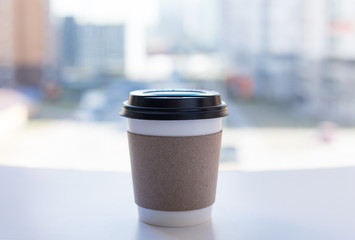 Background with one disposable cup for coffee, city