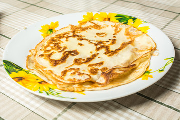 Fried round pancakes in plate on kitchen table.