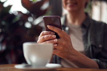 Close up woman messaging on phone in cafe