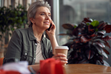 Relaxed smiling woman talking by phone in cafe