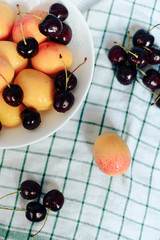 apricots and cherry in a plate on a light background