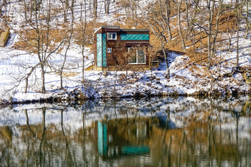 Fototapeta na wymiar House in the forest, in winter and its reflection in the lake. South Korea