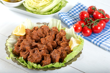 Turkish Food Cig Kofte with lemon, lettuce and parsley on silver plate. 