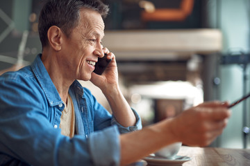 Happy mature man discussing by mobile phone