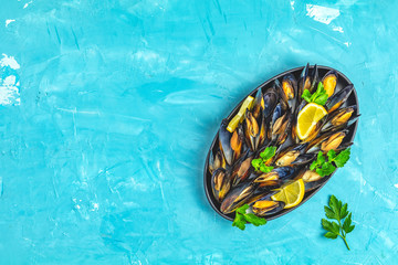 Seafood mussels with lemon and parsley in black metal plate