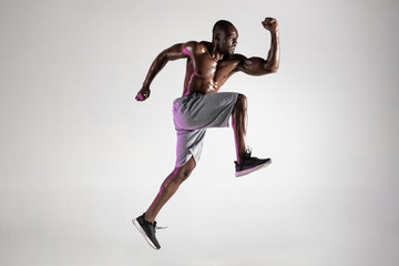 Young african-american bodybuilder training over grey background