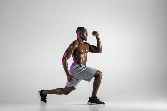 Young african-american bodybuilder training over grey background