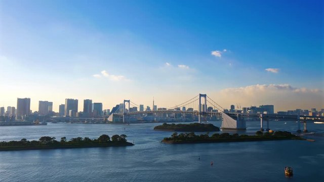 Tokyo time lapse of Rainbow Bridge and bay, cityscape skyline background, blue sunny morning.