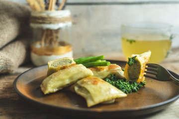 traditional German cuisine, delicious, baked Maultaschen with spinach sauce and green legumes, next...