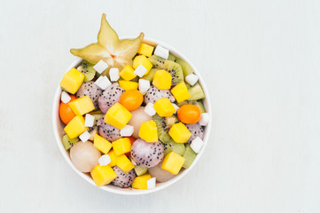 Top view of fresh exotic fruit in bowl. Pieces of white dragon fruit, kiwi, pitaya, mango and starfruit. Tasty vegetarian dessert for eating