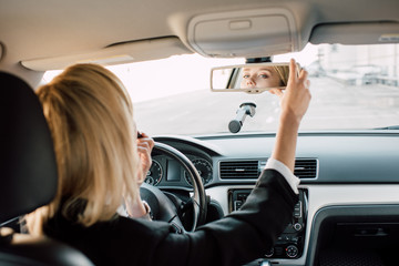 back view of blonde girl touching mirror while sitting in car