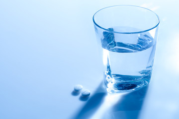 A glass of water with two pills