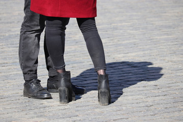 Couple wearing black jeans standing on the street, shadow on pavement. Male and female legs on sidewalk, assignation, denim fashion