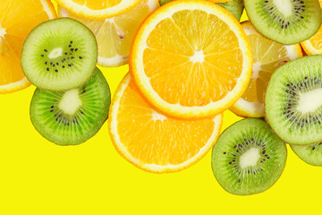 Fototapeta premium citrus slices - kiwi, oranges and lemons on yellow background. Fruits backdrop
