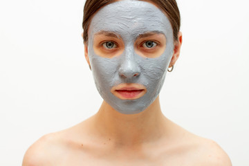 Beautiful woman with a clay  mask on her face. white background