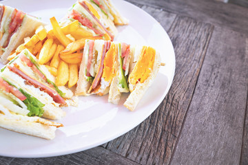 Club sandwich with bacon cheese and ham vegetable and sauce in white plate on table.
