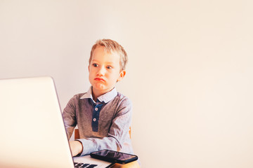 Child 5 years old working on a laptop with an angry face when business failing, humor image.