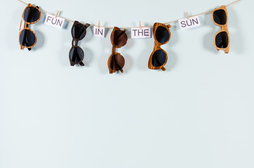 Sunglasses sale concept. Different sunglasses hanging on the rope with phrase fun in the sun on...