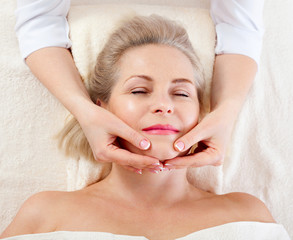 Obraz na płótnie Canvas portrait of beautiful woman in spa environment. middle aged woman doing facial massage in a spa salon