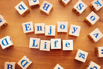 Enjoy life. Conceptual image with the text made from wooden cubes on a desk