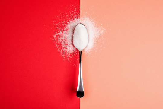 sugar with spoon on red and yellow background