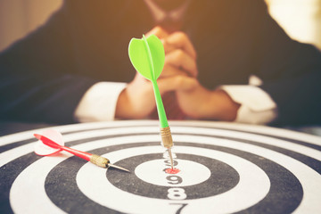 Businessman with dart arrow hit in target center of dartboard, successful business concept