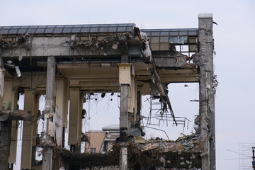 Demolished destructed building ruins. Demolition site in european city. Ruined house on a gray sky on cloudy day