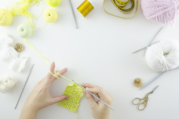 Top view workspace woman knitting with thin knitting needles on a white background. Copy space