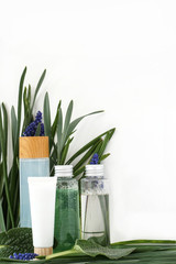 Reusable bottle with liquid. Skin care cosmetics on leaves flower and white background