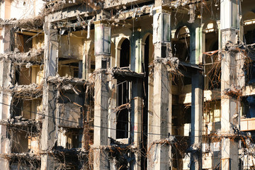 Demolished destructed building ruins. Demolition site in european city. Ruined house on a bright blue sky on a sunny day.
