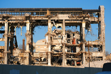 Demolished destructed building ruins. Demolition site in european city. Ruined house on a bright blue sky on a sunny day.