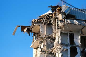 Demolished destructed building ruins. Demolition site in european city. Ruined house on a bright blue sky on a sunny day.