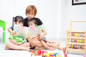 Fototapeta premium Mom is reading comic book with her daughters