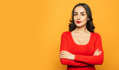 Obraz premium Ladyship. Spicy-orange background with pretty girl in deep red sweater, with matching lip color and crossed hands over her breast.