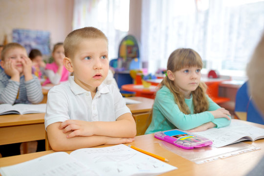 preschool education, children at their desks attentively listen to the teacher in the classroom