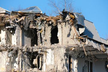 Demolished destructed building ruins. Demolition site in european city. Ruined house on a bright blue sky on a sunny day.