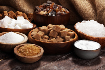 Various types of sugar, brown sugar and white on rustic wooden table