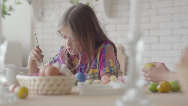 Woman and little girl coloring easter eggs with colors and brush. Preparation for Easter holiday. A happy family.
