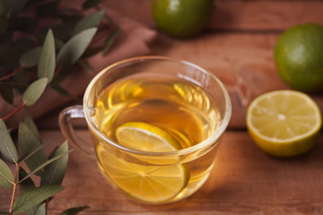 Cup of hot green tea with lime on the old wooden table