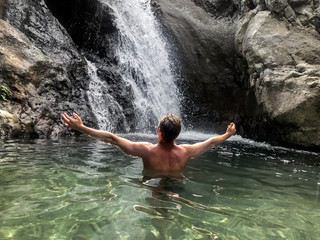 Man standing at lake with waterfall