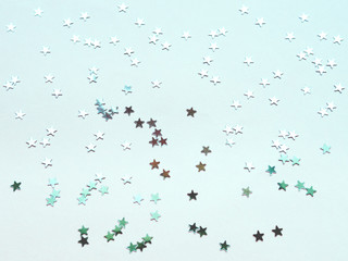 Holiday background with silver star confetti on mint background. Good backdrop for Christmas and New Year cards. Flat lay, top view.