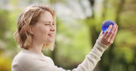 Blonde female holding a blue globe with world map printed on it - Powered by Adobe