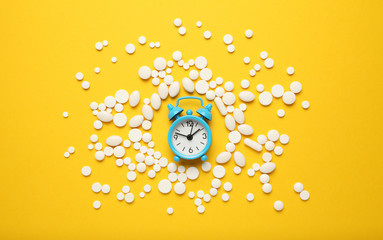 Sleeping pills and an alarm clock, insomnia concept. Drugs for treating sleep problems.