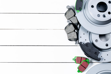 Set of brake discs and pads lies on white boards. View from the top.