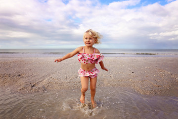 Cute Little Child Splashing and Playing in the Water on the Beach by the Ocean
