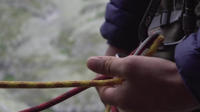 Close up of hands of man belaying climber. Slow motion.