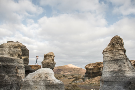 Anonymous female taking pictures of stony terrain