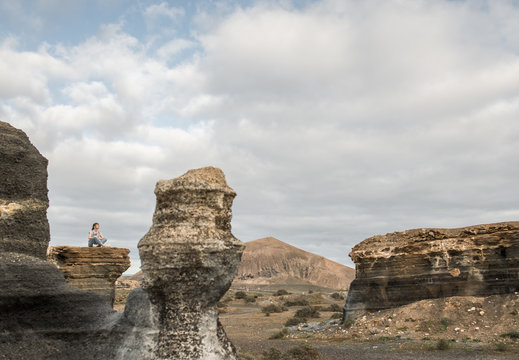Anonymous female sitting of stony terrain