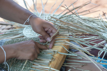  Close up female hands manually weaving sedge bag.Wickerwork bag texture made from dry sedge background.Closeup surface texture of hand made craft work.