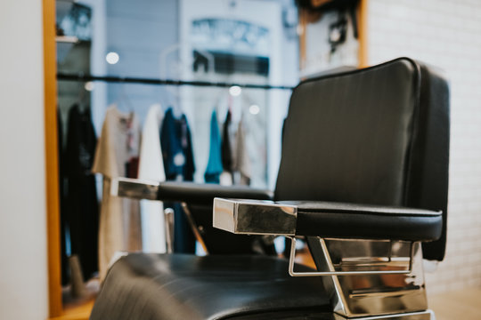 Modern leather chair in barbershop on blurred background